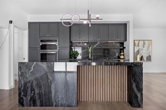 2535 Exline St, Dallas, TX 75215 - kitchen with stainless steel double oven, gray cabinets, dark stone countertops, tasteful backsplash, and wood finished floors