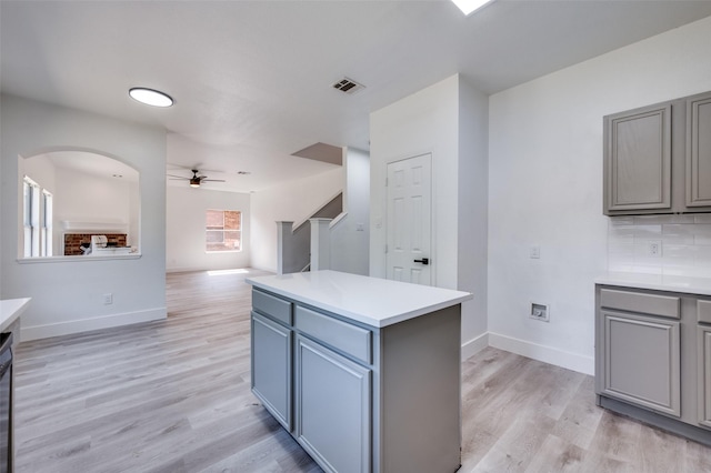 9316 Norfolk Ln, Mckinney, TX 75071 - kitchen with gray cabinetry, a ceiling fan, light wood finished floors, light countertops, and a center island
