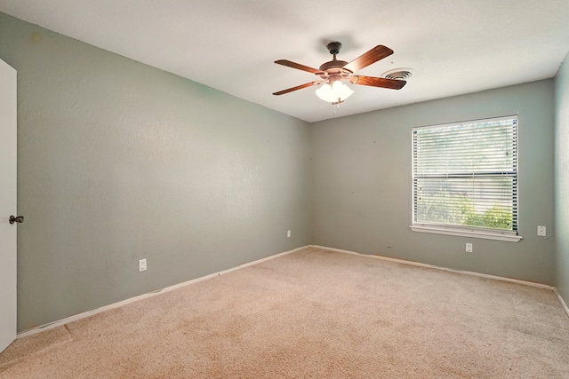 carpeted spare room with a ceiling fan and baseboards