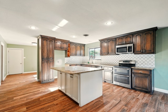 kitchen with stainless steel appliances, a sink, decorative backsplash, dark brown cabinets, and recessed lighting