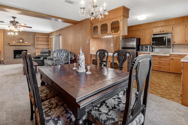 303 Luby Dr, Tom Bean, TX 75489 - dining space featuring light carpet, ceiling fan, a fireplace, a chandelier, and wooden walls