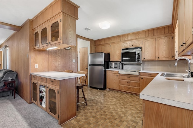 303 Luby Dr, Tom Bean, TX 75489 - kitchen featuring stainless steel appliances, a sink, wooden walls, light countertops, and glass insert cabinets