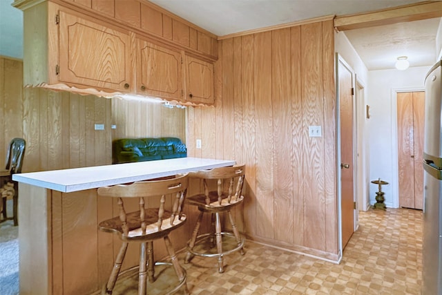 303 Luby Dr, Tom Bean, TX 75489 - kitchen with wood walls, a breakfast bar area, light countertops, light floors, and a peninsula