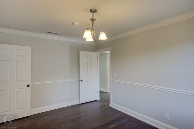 empty room featuring a chandelier, dark wood-type flooring, ornamental molding, and baseboards