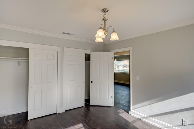 unfurnished bedroom featuring a chandelier, multiple closets, crown molding, baseboards, and dark wood-style floors