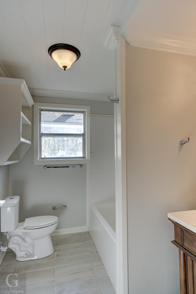 bathroom featuring toilet, a bath, ornamental molding, baseboards, and vanity