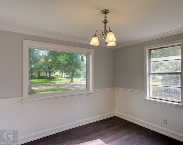 unfurnished room with a chandelier, dark wood finished floors, crown molding, and baseboards