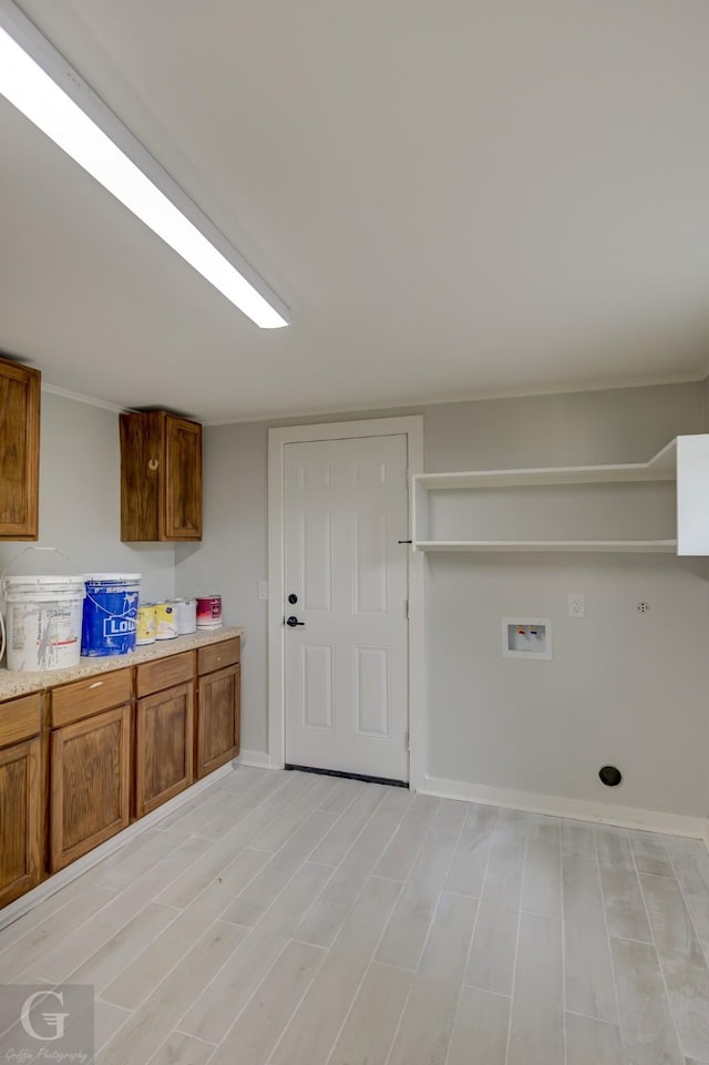 clothes washing area featuring washer hookup, cabinet space, baseboards, and light wood finished floors