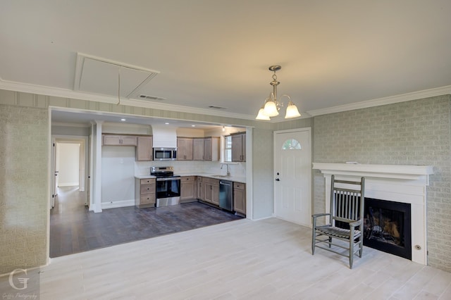 living room with ornamental molding, wood finished floors, attic access, a fireplace, and a chandelier