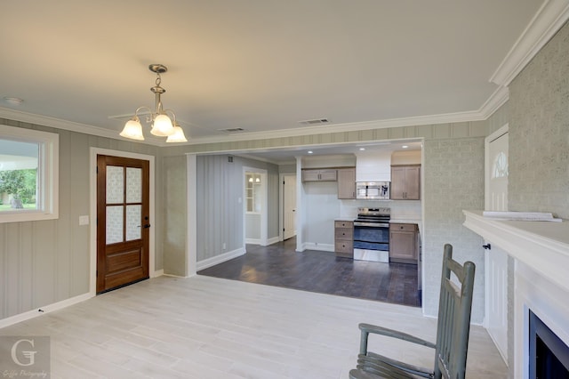 foyer entrance with wood finished floors, ornamental molding, a chandelier, and baseboards