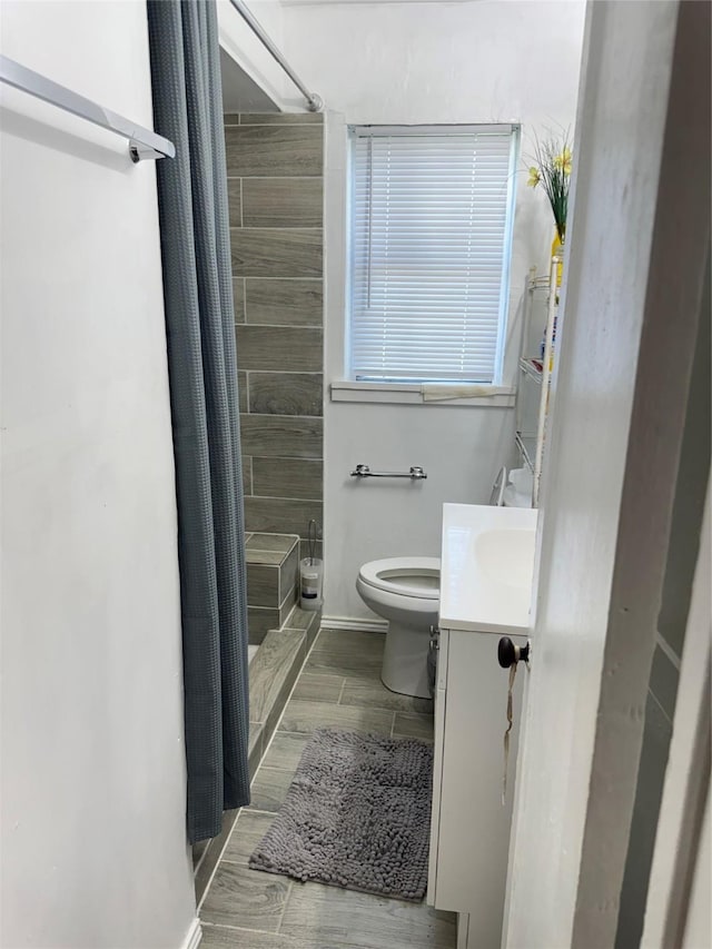 2414 Marfa Ave, Dallas, TX 75216 - full bath with vanity, tiled shower, toilet, and wood finished floors
