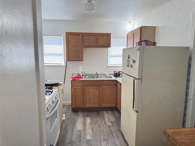 2414 Marfa Ave, Dallas, TX 75216 - kitchen with white appliances, a sink, light wood-style floors, brown cabinets, and light countertops