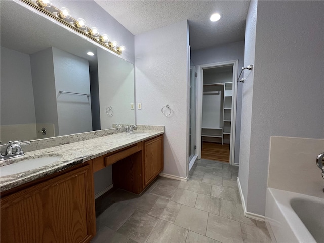 920 Joshua Dr, Burleson, TX 76028 - bathroom with a spacious closet, baseboards, double vanity, a textured ceiling, and a shower