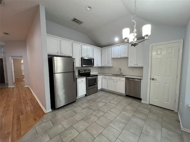 920 Joshua Dr, Burleson, TX 76028 - kitchen featuring stainless steel appliances, a sink, lofted ceiling, light countertops, and a chandelier