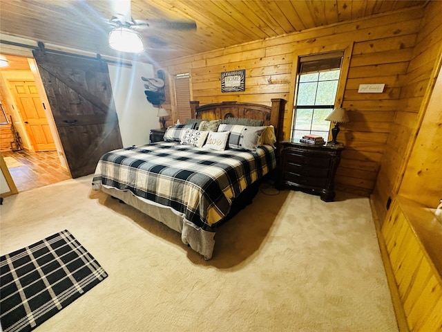 637 County Road 4420, Winnsboro, TX 75494 - bedroom featuring wooden walls, a barn door, light carpet, wooden ceiling, and a ceiling fan