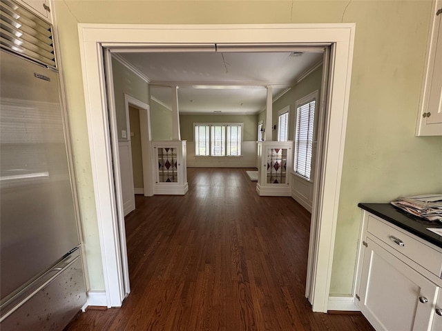 hallway featuring ornamental molding, dark wood-type flooring, and baseboards