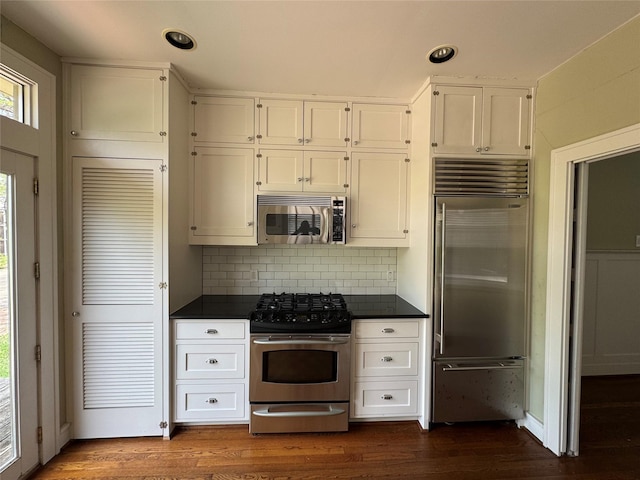 kitchen with appliances with stainless steel finishes, dark countertops, white cabinets, backsplash, and recessed lighting