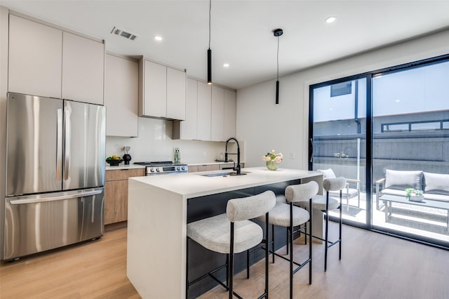 7304 Flyers Way, Dallas, TX 75235 - kitchen featuring stainless steel appliances, a sink, modern cabinets, light wood-style floors, and a kitchen bar