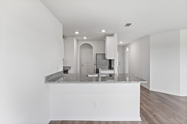 4703 Fillmore Dr, Greenville, TX 75401 - kitchen featuring arched walkways, freestanding refrigerator, light stone counters, white cabinetry, and recessed lighting