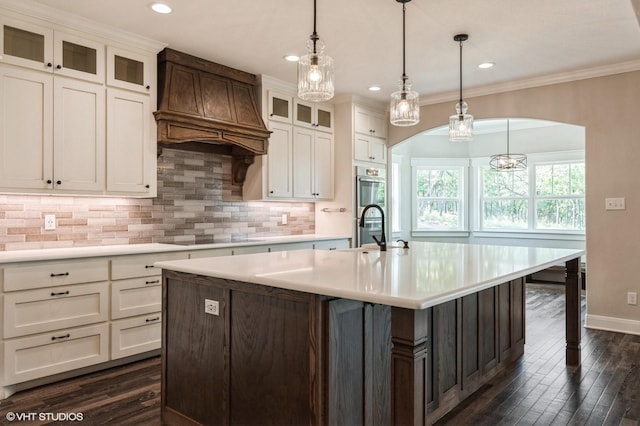 344 Whispering Oaks Trl, Sunset, TX 76270 - kitchen featuring arched walkways, black electric stovetop, light countertops, custom exhaust hood, and tasteful backsplash