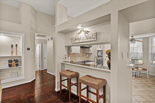 3507 Jasmine Ln, Rowlett, TX 75089 - kitchen with appliances with stainless steel finishes, a breakfast bar, white cabinets, ceiling fan, and baseboards
