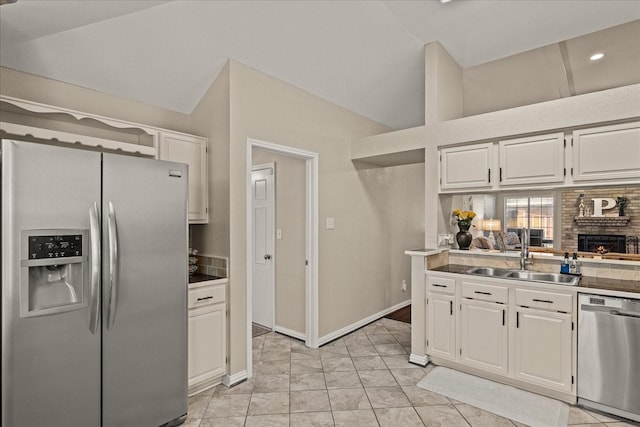 3507 Jasmine Ln, Rowlett, TX 75089 - kitchen with stainless steel appliances, a sink, vaulted ceiling, white cabinetry, and a brick fireplace