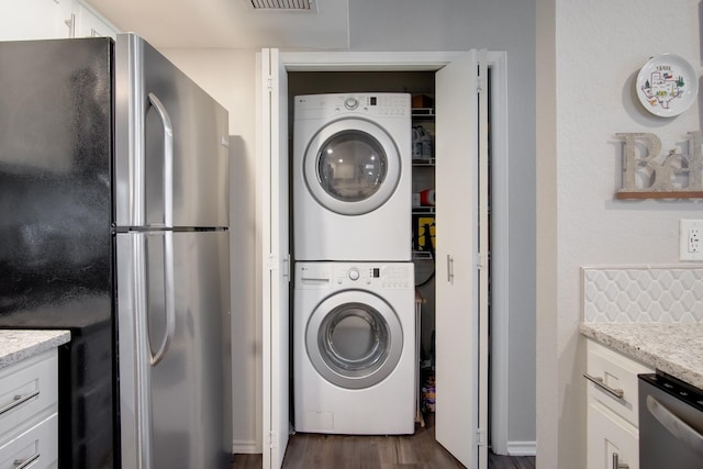 626 Lochngreen Trl, Arlington, TX 76012 - clothes washing area featuring stacked washing machine and dryer and dark wood-style flooring