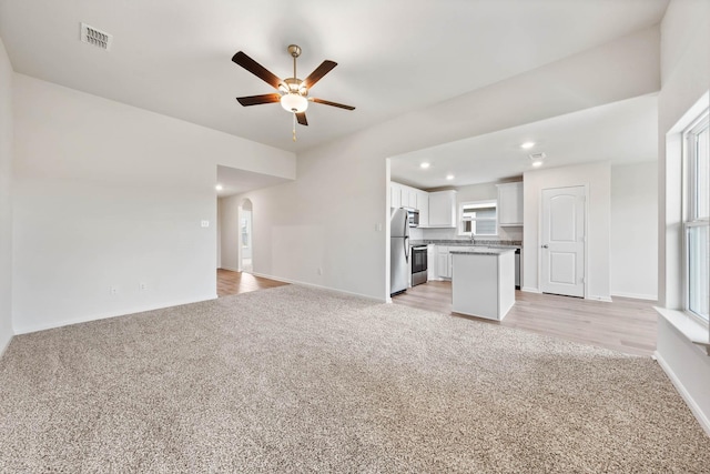 4809 Fillmore Dr, Greenville, TX 75401 - unfurnished living room featuring light colored carpet, ceiling fan, arched walkways, recessed lighting, and baseboards