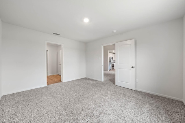 4809 Fillmore Dr, Greenville, TX 75401 - unfurnished bedroom with light carpet, stainless steel refrigerator, baseboards, and recessed lighting