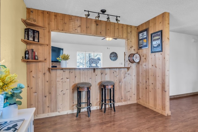 836 Silver Creek Rd, Azle, TX 76020 - bar area with dark wood-style floors, wooden walls, track lighting, baseboards, and ceiling fan
