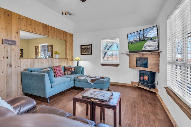 836 Silver Creek Rd, Azle, TX 76020 - living room featuring a wood stove, wood finished floors, wood walls, a ceiling fan, and baseboards