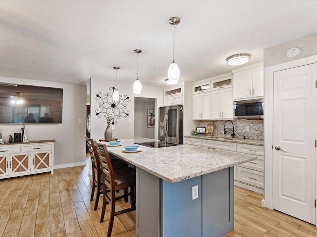 5601 Briarcrest Dr, Garland, TX 75043 - kitchen featuring stainless steel appliances, a sink, light wood finished floors, white cabinets, and a breakfast bar area