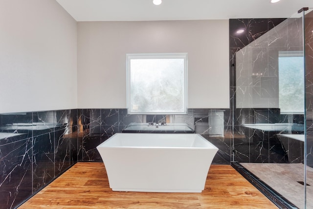 808 N Main St, Tioga, TX 76233 - bathroom with a freestanding bath, recessed lighting, tile walls, a marble finish shower, and wood finished floors