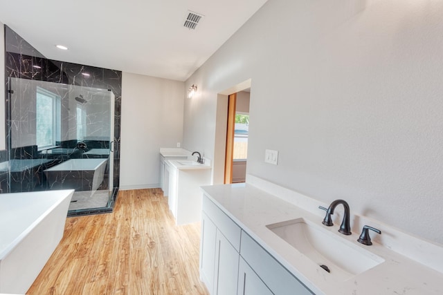 808 N Main St, Tioga, TX 76233 - bathroom with two vanities, a shower stall, wood finished floors, and a freestanding tub