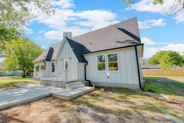 808 N Main St, Tioga, TX 76233 - rear view of house with board and batten siding, roof with shingles, fence, a patio area, and a chimney