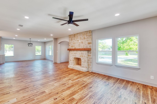808 N Main St, Tioga, TX 76233 - unfurnished living room with arched walkways, light wood finished floors, baseboards, a stone fireplace, and recessed lighting