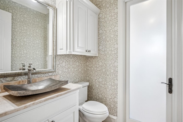 bathroom featuring wallpapered walls, toilet, and vanity