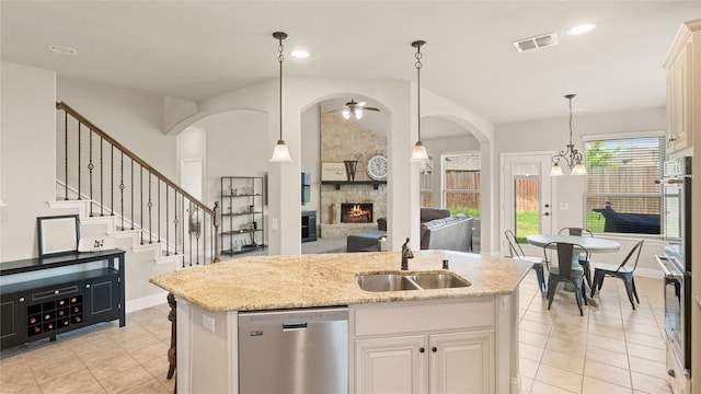 5100 Ambergate Ln, Sherman, TX 75092 - kitchen with appliances with stainless steel finishes, a sink, a fireplace, arched walkways, and light tile patterned flooring