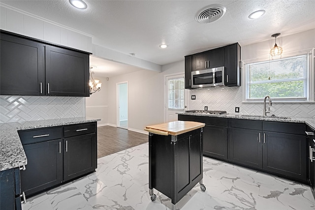 315 Westway Dr, Rockwall, TX 75087 - kitchen featuring stainless steel appliances, a sink, light marble finish flooring, dark cabinets, and a textured ceiling