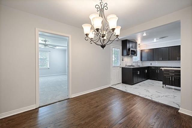 315 Westway Dr, Rockwall, TX 75087 - kitchen with stainless steel microwave, a chandelier, wood finished floors, dark cabinetry, and plenty of natural light
