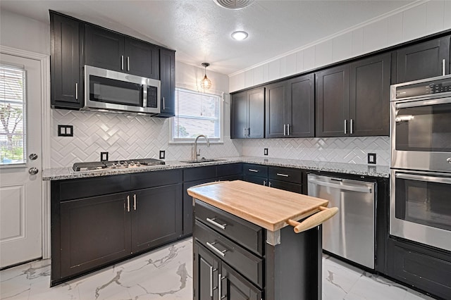 315 Westway Dr, Rockwall, TX 75087 - kitchen featuring appliances with stainless steel finishes, a sink, light marble finish floors, backsplash, and crown molding