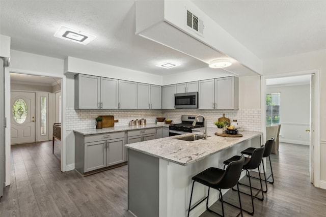 6908 Heatherknoll Dr, Dallas, TX 75248 - kitchen featuring stainless steel appliances, gray cabinetry, a sink, and a kitchen breakfast bar