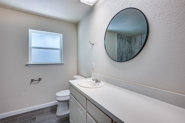 5217 Mack Rd, Haltom City, TX 76117 - bathroom with wood finish floors, toilet, baseboards, and vanity
