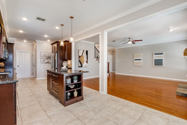 kitchen with ceiling fan, light tile patterned floors, ornamental molding, dark stone countertops, and dark brown cabinetry