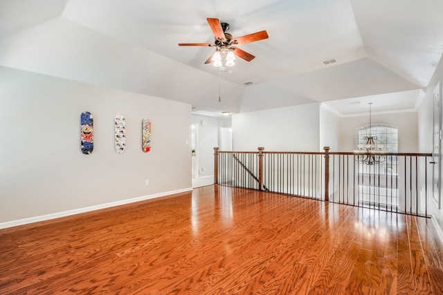 spare room featuring a chandelier, a ceiling fan, wood finished floors, vaulted ceiling, and baseboards