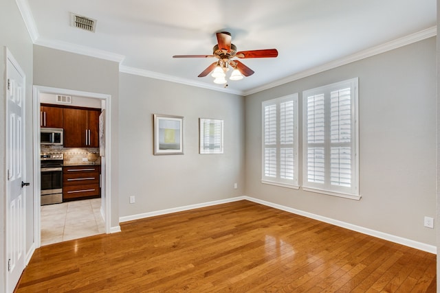 spare room featuring a ceiling fan, light wood-style flooring, crown molding, and healthy amount of natural light