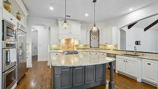 kitchen featuring a sink, built in appliances, gray cabinets, a kitchen island, and white cabinets