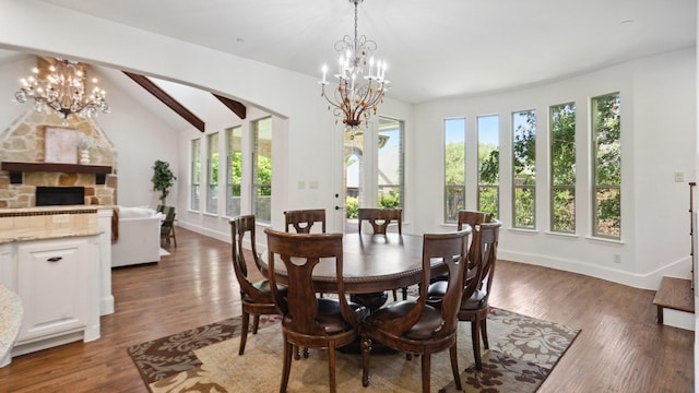 dining space featuring a chandelier, wood finished floors, and a stone fireplace