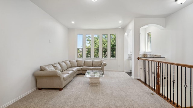 carpeted living room featuring arched walkways, baseboards, and recessed lighting