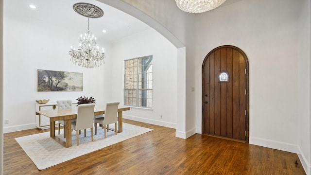 dining room with a chandelier, arched walkways, wood finished floors, and recessed lighting